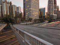 a wide open freeway, with tall buildings along both sides and on both side of it, are lit at dusk