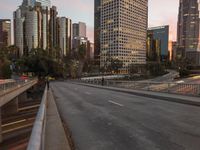 a wide open freeway, with tall buildings along both sides and on both side of it, are lit at dusk