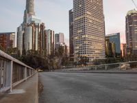 a wide open freeway, with tall buildings along both sides and on both side of it, are lit at dusk