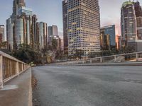 a wide open freeway, with tall buildings along both sides and on both side of it, are lit at dusk