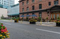 street scene with large flowered planters in front of buildings and a paved road