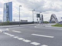 the intersection on a deserted day with cars passing by and buildings in the background and blue sky with clouds
