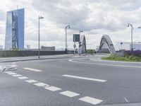 the intersection on a deserted day with cars passing by and buildings in the background and blue sky with clouds