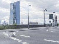 the intersection on a deserted day with cars passing by and buildings in the background and blue sky with clouds