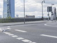 the intersection on a deserted day with cars passing by and buildings in the background and blue sky with clouds