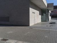 a street is in front of a building next to a street with benches and signs on it