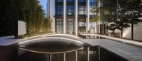 a bridge crosses over a reflecting pool near a tall building on either side of a street