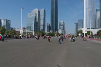 a group of people walking down the middle of a street near tall buildings in the background