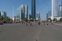 a group of people walking down the middle of a street near tall buildings in the background