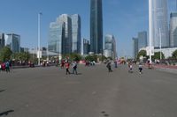 a group of people walking down the middle of a street near tall buildings in the background