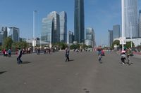 a group of people walking down the middle of a street near tall buildings in the background