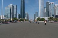 a group of people walking down the middle of a street near tall buildings in the background