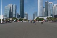 a group of people walking down the middle of a street near tall buildings in the background