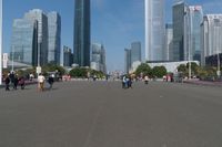 a group of people walking down the middle of a street near tall buildings in the background