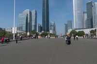 a group of people walking down the middle of a street near tall buildings in the background