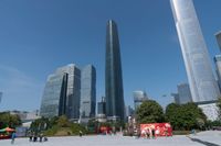 tall buildings with a blue sky in the background and people on the street on bicycles