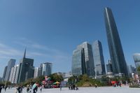 tall buildings with a blue sky in the background and people on the street on bicycles