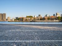 there is a woman that is standing with a skateboard by the water in the city