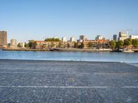 there is a woman that is standing with a skateboard by the water in the city