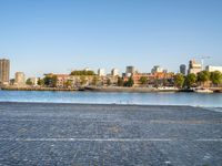 there is a woman that is standing with a skateboard by the water in the city