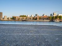 there is a woman that is standing with a skateboard by the water in the city