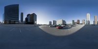 a city is seen through a fish - eye lens with cars parked in the lot