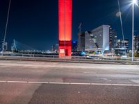 the city skyline is illuminated at night from under the bridge on a street in front of the road is a busy highway