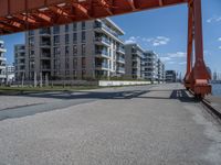 an industrial structure with a single pole on the ground near a street and two apartment buildings