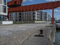 an industrial structure with a single pole on the ground near a street and two apartment buildings