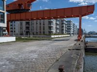 an industrial structure with a single pole on the ground near a street and two apartment buildings