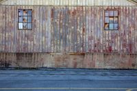 two windows in the side of an old building that needs to be painted or remodeled