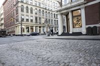 several large buildings line the city streets and a car is stopped at a traffic light