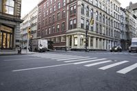 several large buildings line the city streets and a car is stopped at a traffic light
