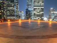 a city skyline at night with streetlights and illuminated buildings on the foreground and a fountain in the middle of the circle