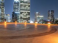 a city skyline at night with streetlights and illuminated buildings on the foreground and a fountain in the middle of the circle