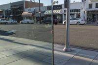 some cars and people on a city street and traffic signals and cars parked in front