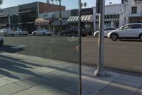 some cars and people on a city street and traffic signals and cars parked in front