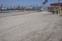 a parking lot that has gravel on it and flags hanging from the poles over it