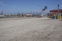 a parking lot that has gravel on it and flags hanging from the poles over it