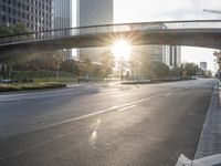 a street filled with a bridge over a road filled with tall buildings on both sides