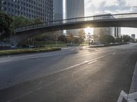 a street filled with a bridge over a road filled with tall buildings on both sides