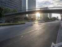 a street filled with a bridge over a road filled with tall buildings on both sides