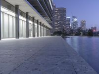 a person sitting on a skateboard in a courtyard next to an open area with tall buildings