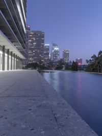 a person sitting on a skateboard in a courtyard next to an open area with tall buildings