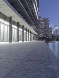 a person sitting on a skateboard in a courtyard next to an open area with tall buildings