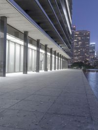 a person sitting on a skateboard in a courtyard next to an open area with tall buildings