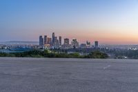 an open area with some benches in front of a large city skyline and blue sky