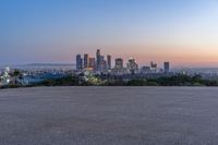 an open area with some benches in front of a large city skyline and blue sky