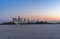 an open area with some benches in front of a large city skyline and blue sky