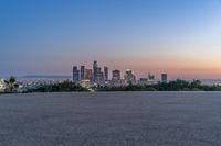 an open area with some benches in front of a large city skyline and blue sky